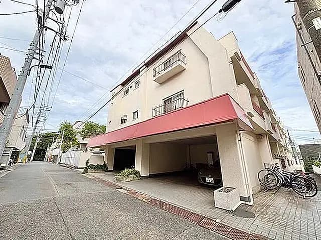 - 駐車場のある3階建てのマンション、赤い屋根と周囲には電柱や自転車ラックが配置された街並みの風景
