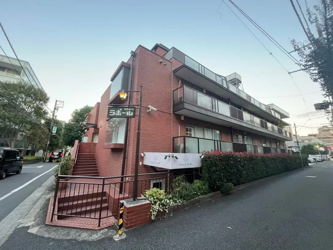 夕暮れ時の住宅街にある赤レンガのアパート建物、街路樹と歩道が見える静かな風景