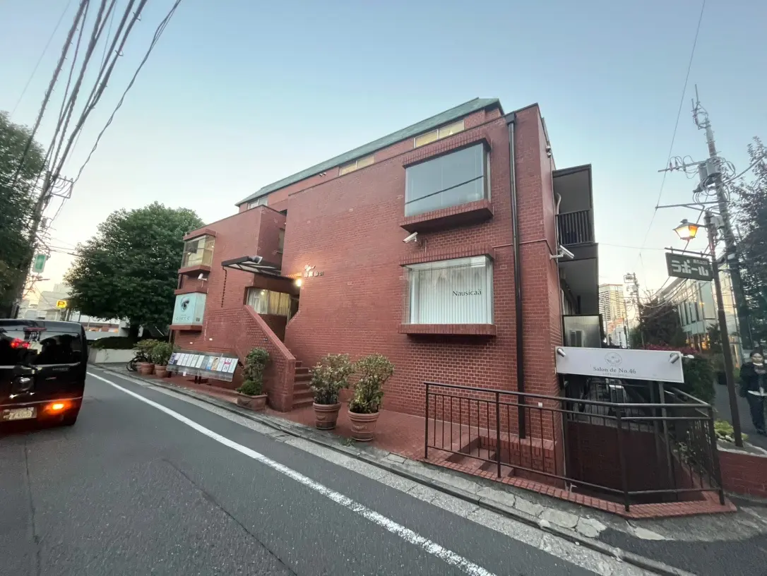 都会の通りに面したレンガ造りの建物、夕暮れ時のサロン外観