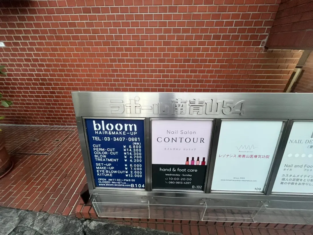 レンガ壁のビルに設置された美容室とネイルサロンの案内看板
