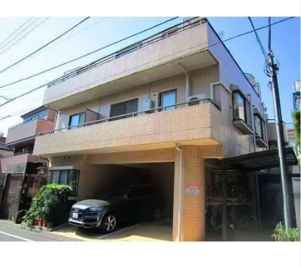 - ピンクのタイルで覆われた二階建ての住宅、1階に車が停まっているカーポートとベランダがある外観の写真