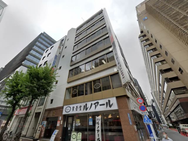 - 高層ビルの外観、1階に「リトルアール」の看板があり、周囲には他のビルが立ち並ぶ商業エリアの風景