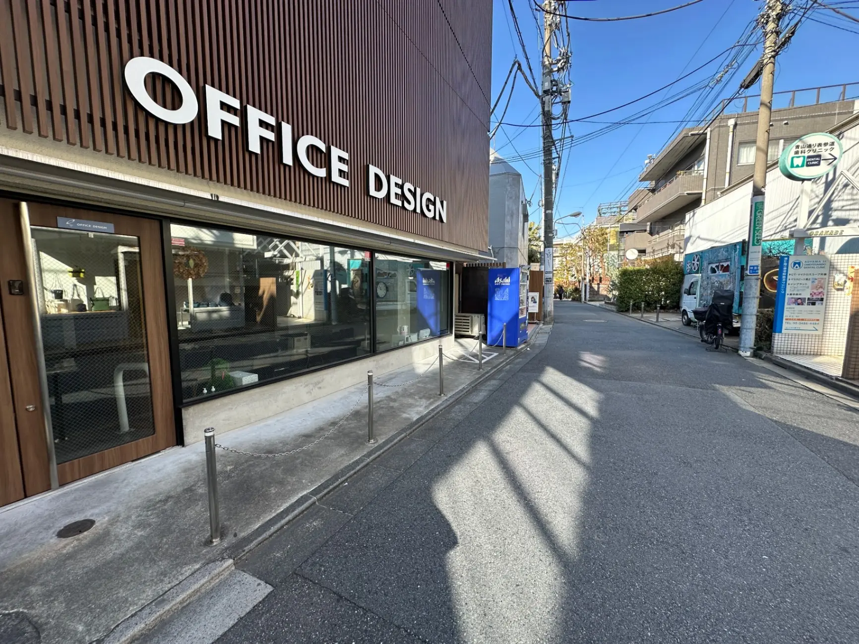 オフィスデザインの看板が目立つ都会のオフィス街、晴天の下での歩道と道路