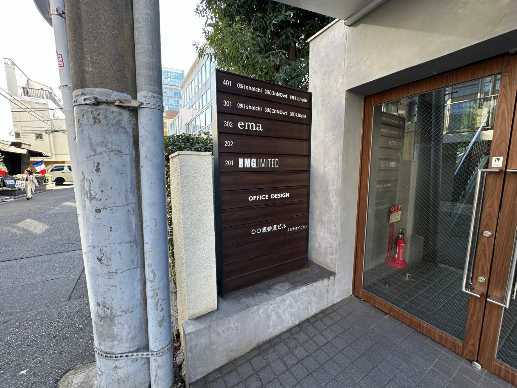 都会のオフィスビル入り口、入居企業の看板、人通りのある歩道