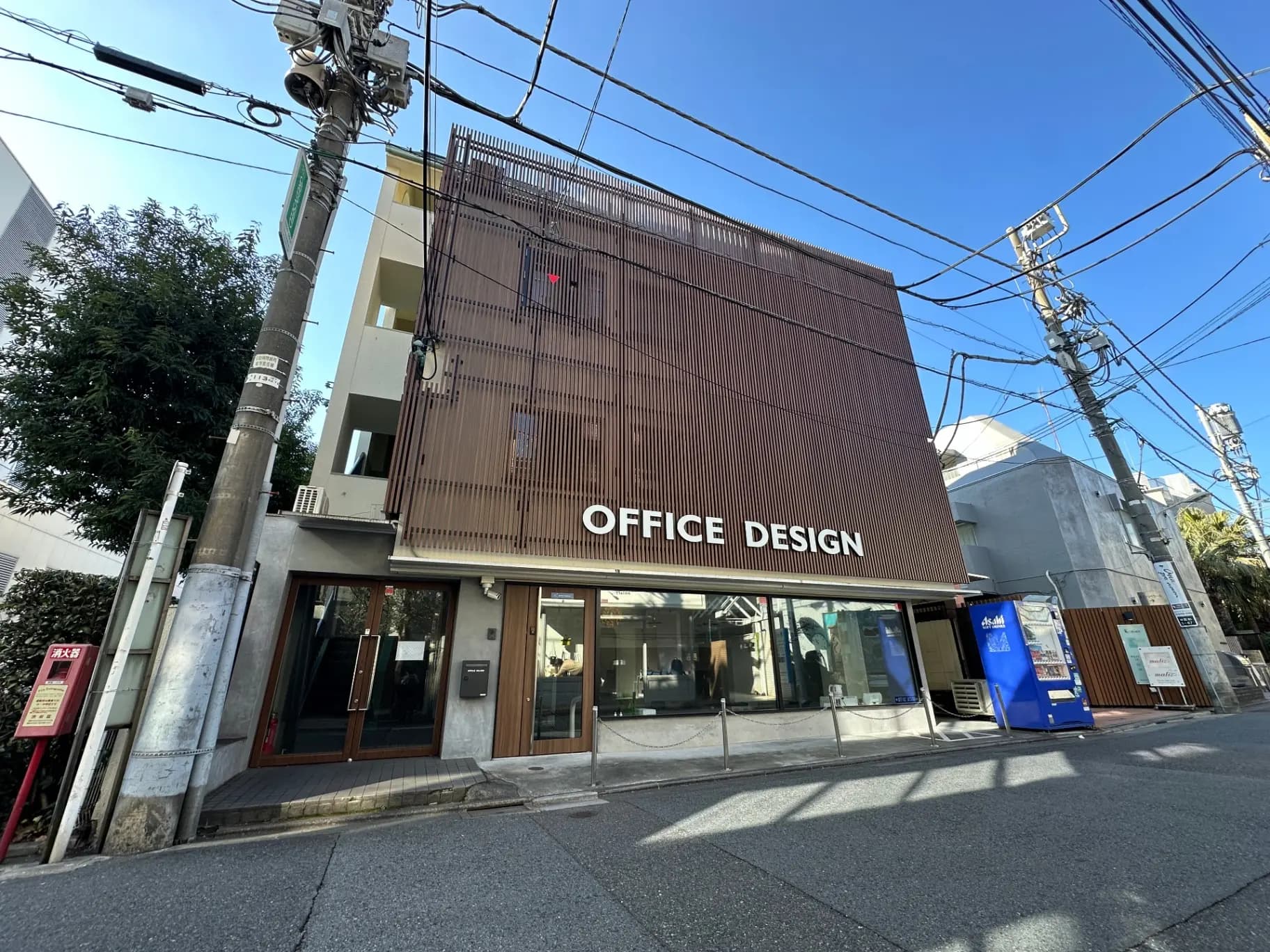 モダンなオフィスデザインの外観、茶色の外壁と看板、都市の電柱と配線が見える