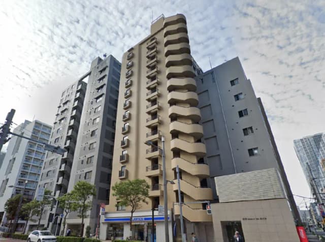- 都市の風景に映える高層マンション、特徴的なバルコニーと周囲の建物が並ぶ街並み