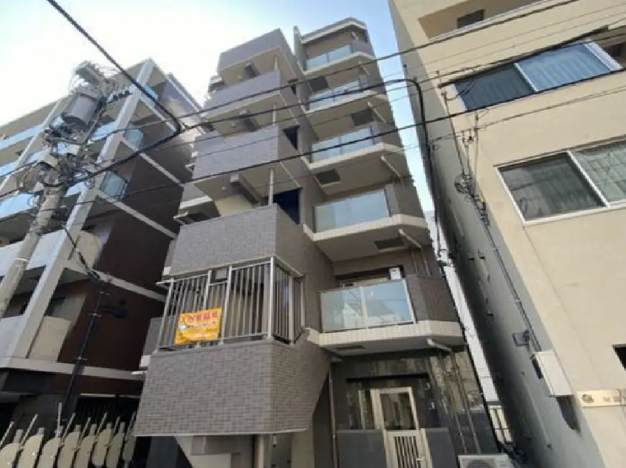 - 現代的なデザインの新築マンション、全体がグレーのタイル張り、バルコニー付きの間取り、周囲に建物が立ち並ぶ街並み