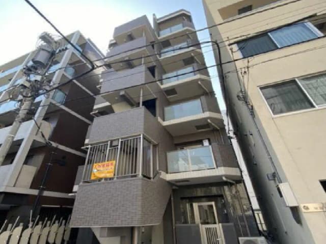 - 現代的なデザインの新築マンション、全体がグレーのタイル張り、バルコニー付きの間取り、周囲に建物が立ち並ぶ街並み