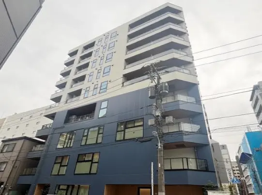 - 現代的なデザインの集合住宅、ガラスバルコニーを備えた複数階の外観、周囲の都市風景と電柱が見える景観