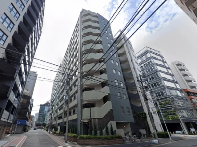 - 都市の街並みにあるモダンなマンション、周囲のビルと電線が交差する風景