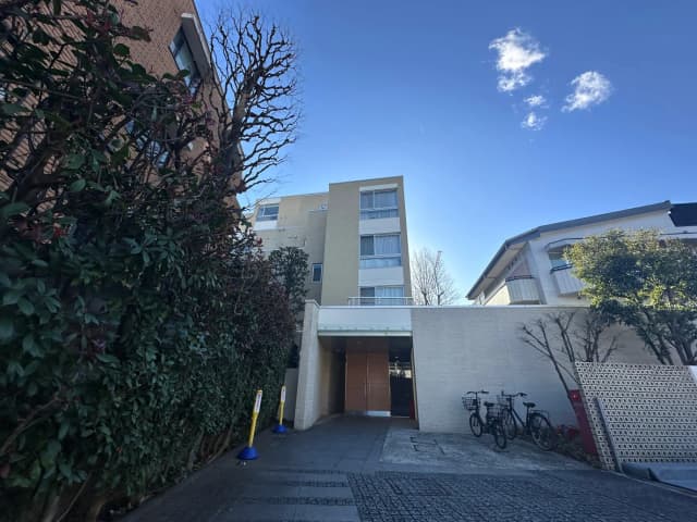 都会的な住宅街の風景、モダンな建物と緑豊かな植栽、青空と雲が美しい日中の写真