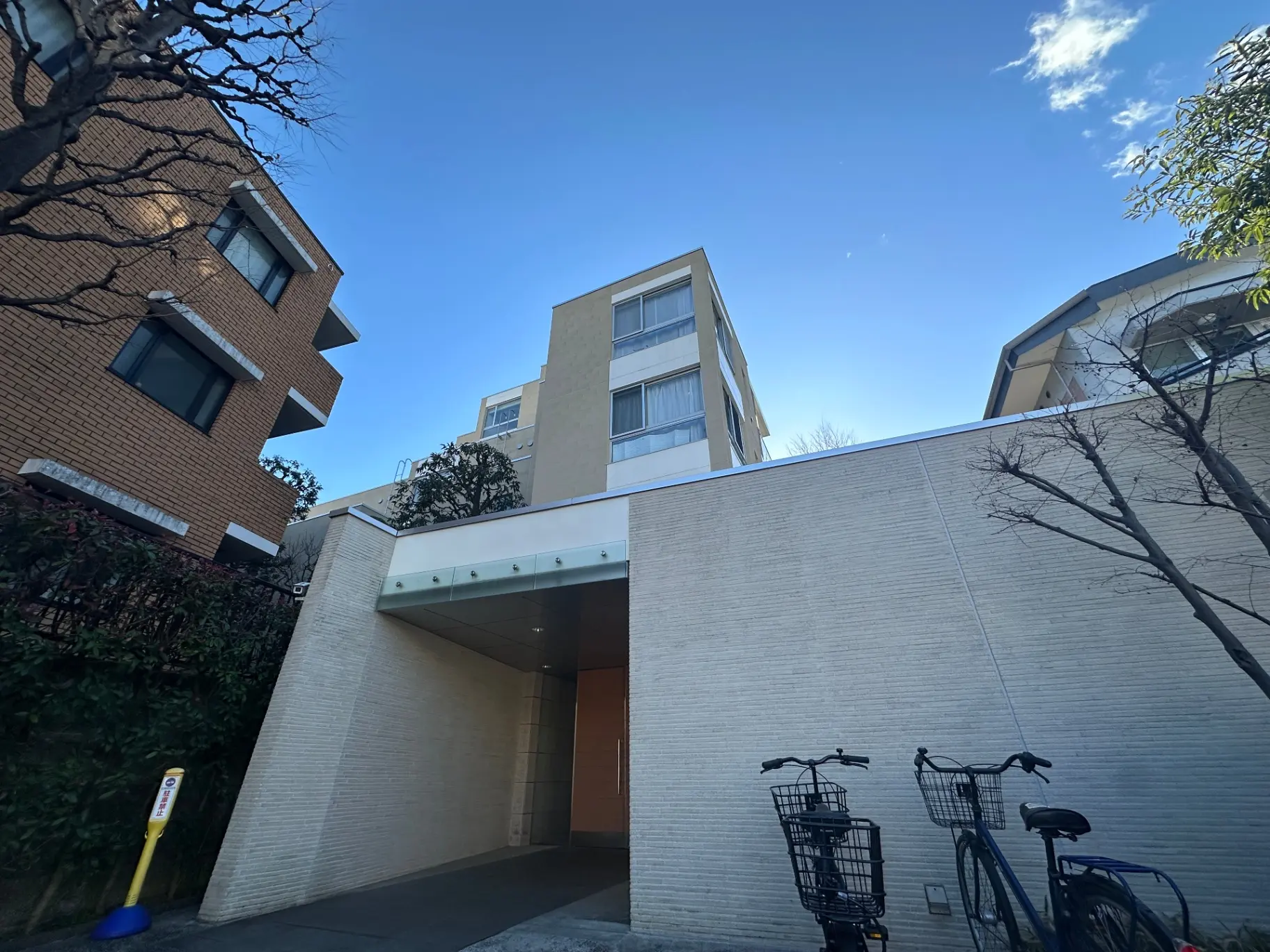 現代的なデザインのマンションエントランス、自転車駐輪場、青空と建物のコントラスト