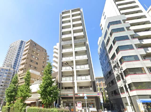 - 高層マンションと周辺のビル、青空を背景にした都市の風景、緑豊かな街並みの様子