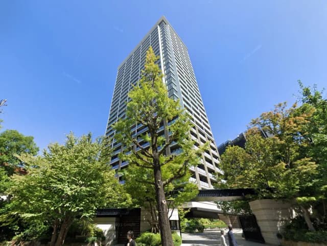 新緑に囲まれたモダンな高層マンション、青空の下の都市風景