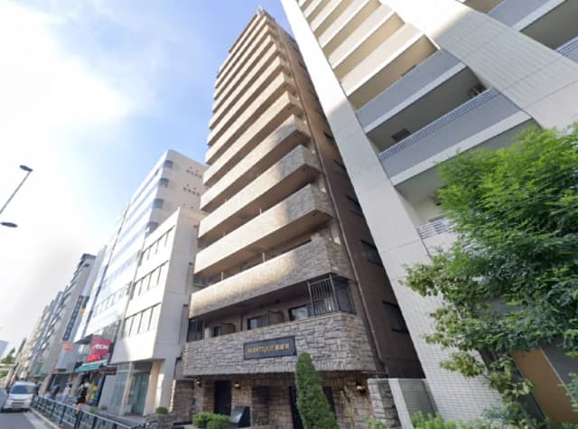 新しいデザインの分譲マンション、外観はモダンで石造りのエントランスが特徴、周囲には高層ビルが立ち並ぶ環境