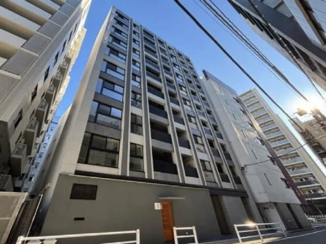 - 都市の中に佇む現代的なデザインのマンション、青空を背景にした高層建築の外観