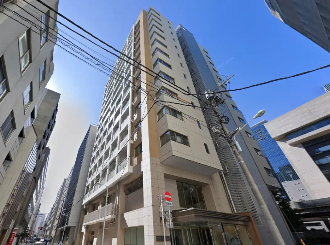 - 高層ビルが立ち並ぶ都市の風景、手前には近代的なデザインのビルと電線が見える外観