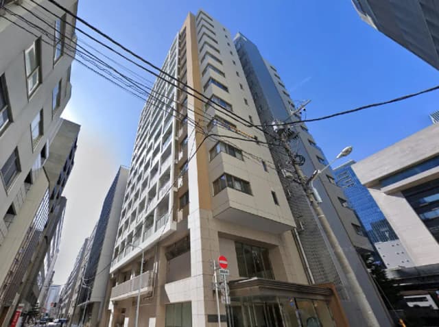 - 高層ビルが立ち並ぶ都市の風景、手前には近代的なデザインのビルと電線が見える外観