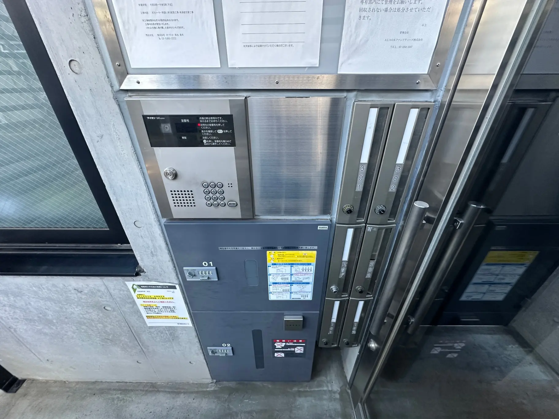 オートロック機能付きのマンションエントランスドア、インターホンと宅配ボックスが設置されたセキュリティ面に配慮した玄関