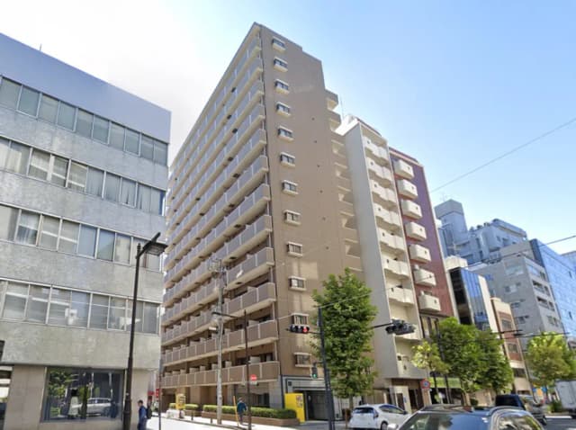 - 都市の風景に佇むモダンな高層マンション、周囲にオフィスビルや商業施設が立ち並ぶエリア