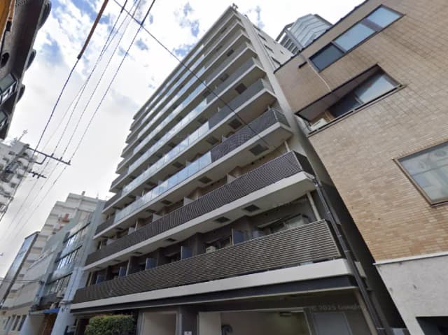 - シンプルでモダンなデザインのマンションの外観、バルコニーと隣接する建物の様子が見える街並み