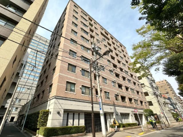 - モダンなデザインのマンション外観、近隣の建物や樹木が映る街角の風景