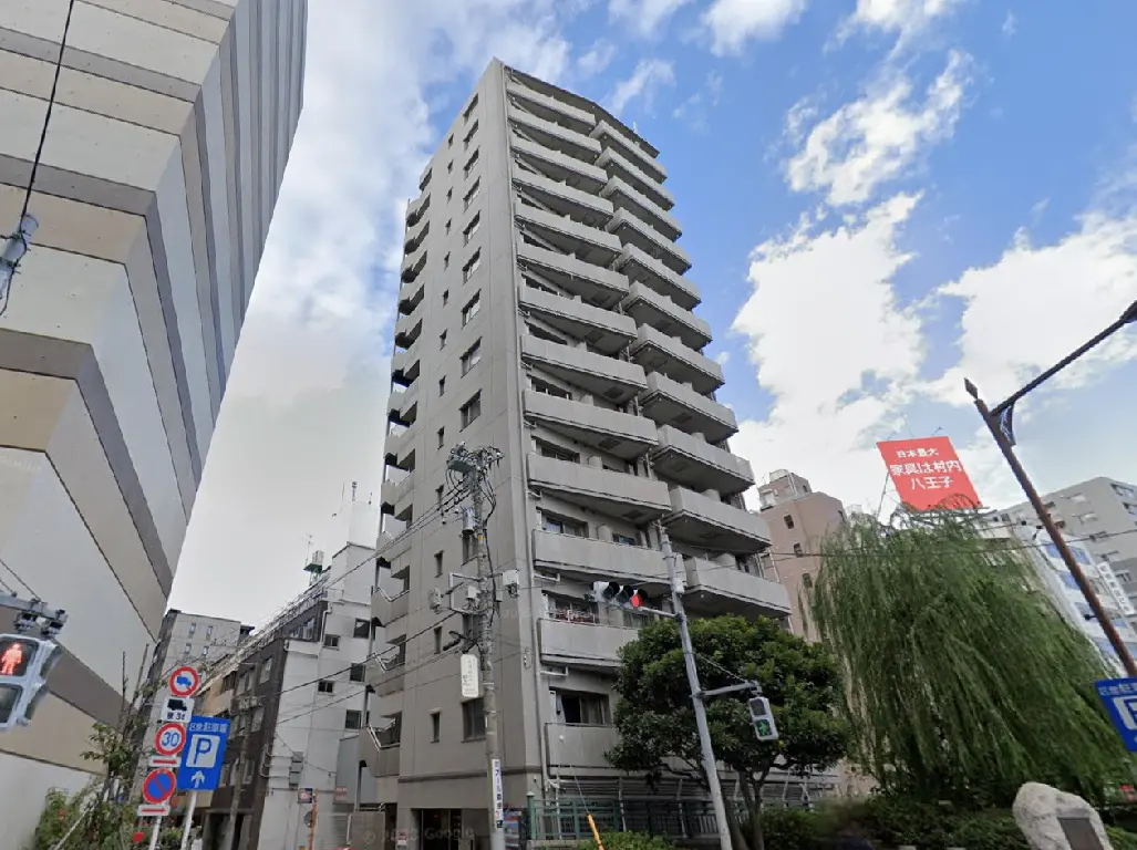- 高層マンションの外観、周囲に立ち並ぶ建物と青空を背景にした都市風景
