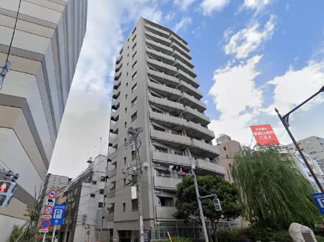 - 高層マンションの外観、周囲に立ち並ぶ建物と青空を背景にした都市風景