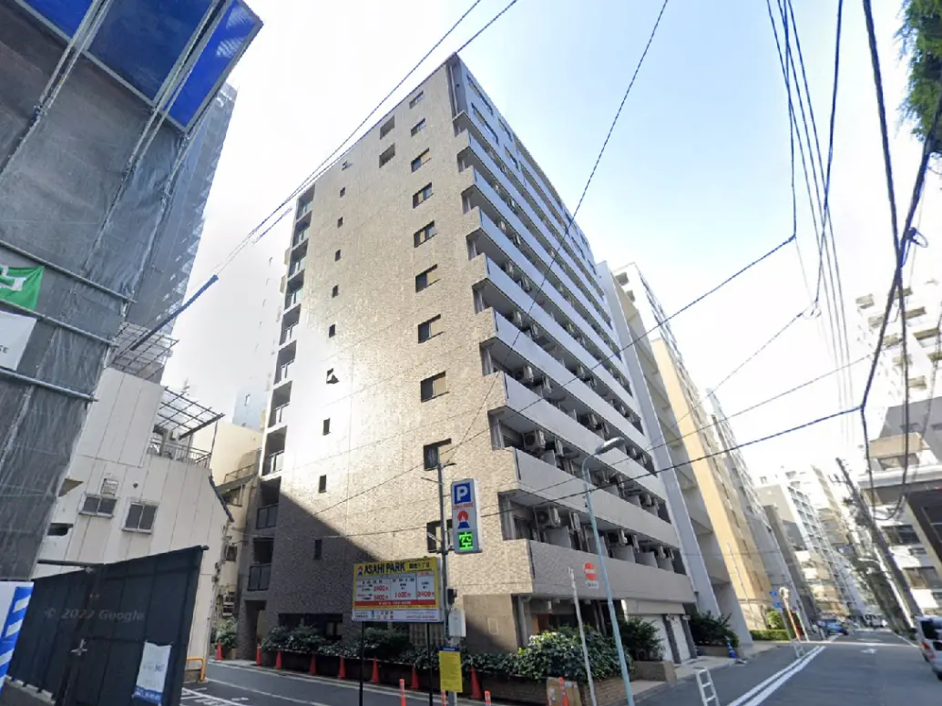 - 都市に建つ現代的なマンション、周囲に他の高層ビルや工事中の建物、丁寧な配色の外観が特徴的な街並み