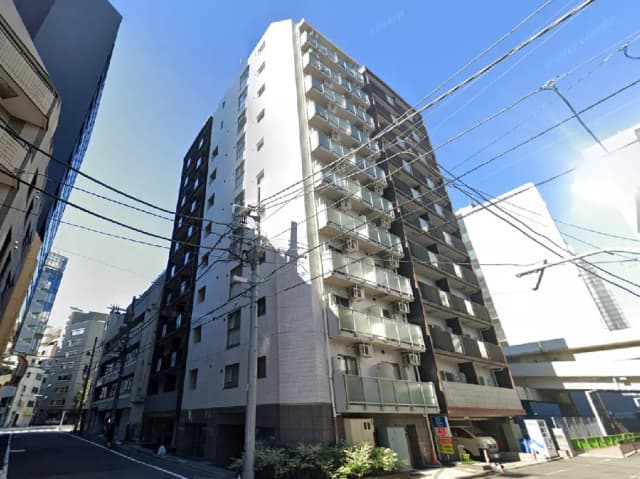 - 近代的な高層マンションの外観、周囲のビルと電線が交錯する街並みの風景