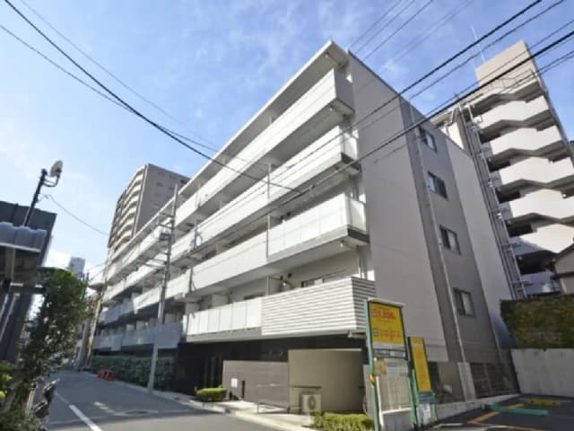 - 現代的なデザインのマンション外観、バルコニーのある構造、周囲の都市景観と青空が広がるシーン