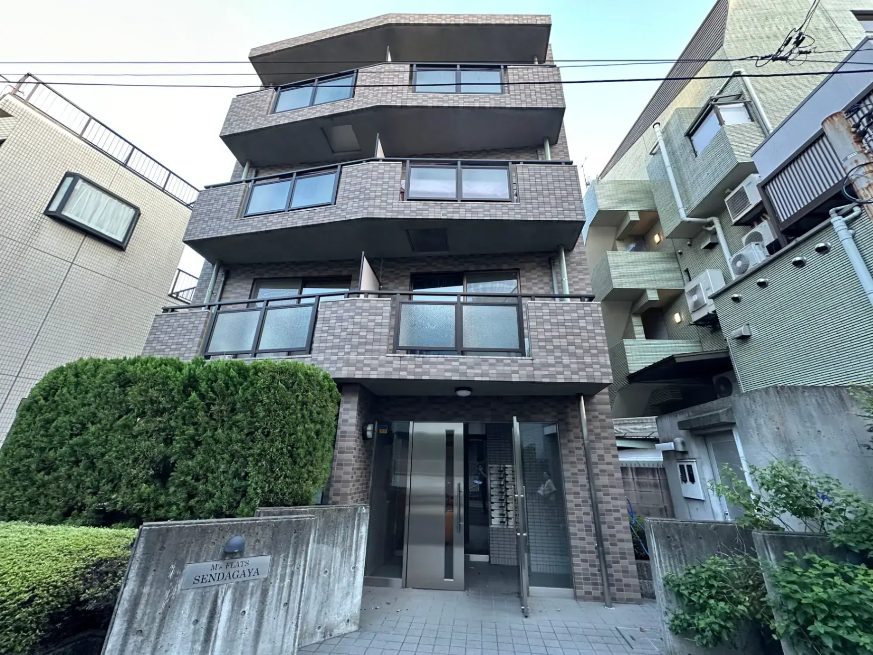 モダンなデザインの多層住宅の外観、整備された緑の植栽