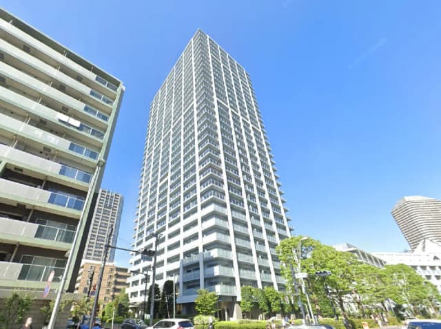 - 高層マンションの外観、青空の下に立ち並ぶ現代的な住宅ビルと周囲の緑豊かな景観