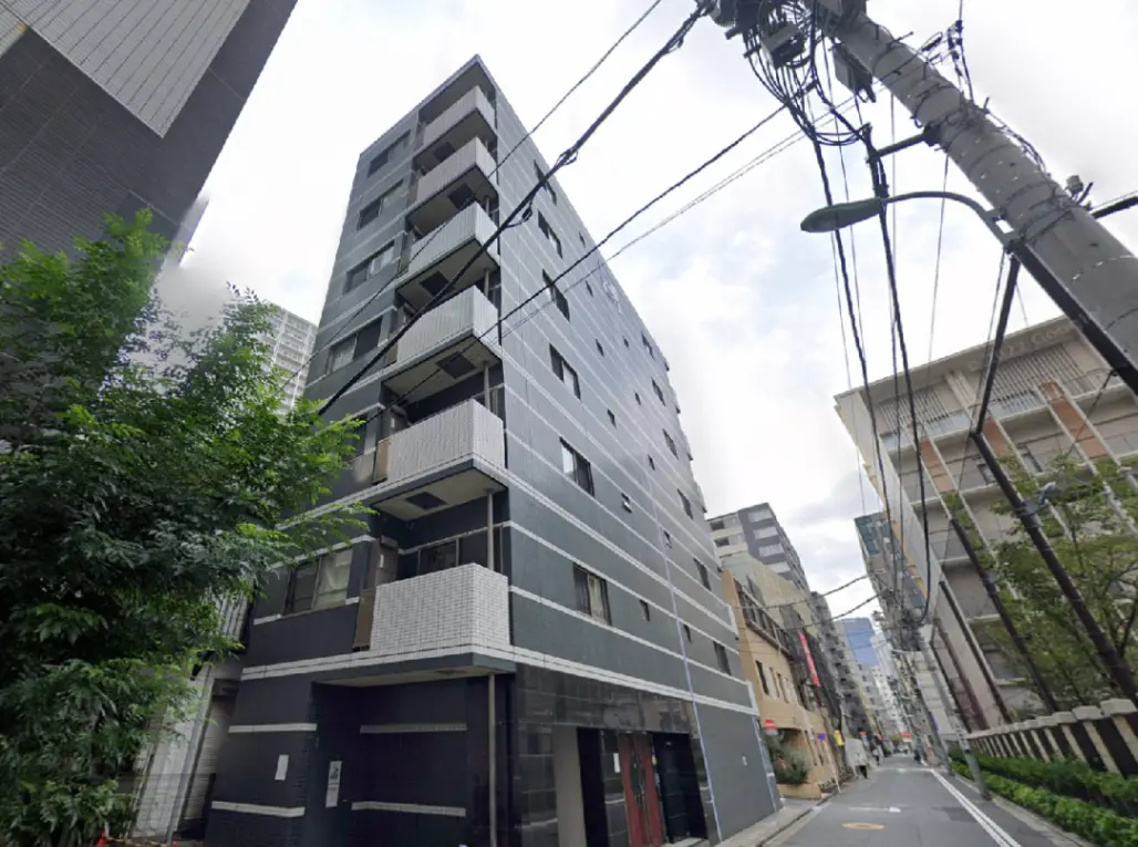 - モダンな外観の低層マンション、周囲には緑と街並みが広がり、電線が交差する都会の景色