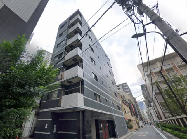 - モダンな外観の低層マンション、周囲には緑と街並みが広がり、電線が交差する都会の景色
