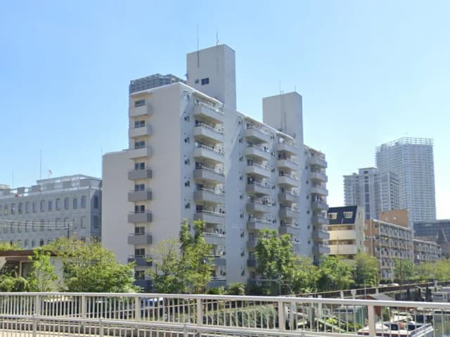 - 白い外壁のマンション、3階建てのバルコニー付き、青空の下に立つ都市の風景