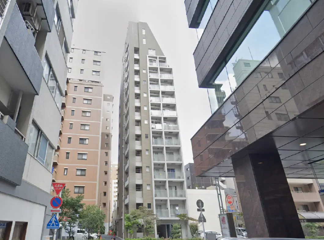 - 都市部の住宅街に立つ高層マンション、隣接する建物や通りの風景が広がるシーン