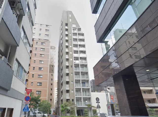 - 都市部の住宅街に立つ高層マンション、隣接する建物や通りの風景が広がるシーン