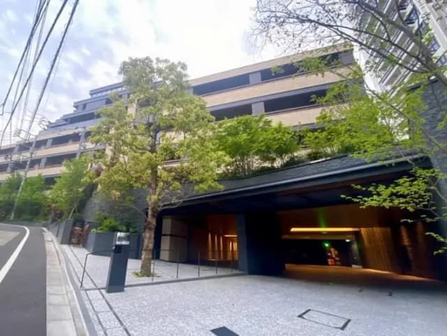 - モダンな建物と緑豊かな植栽、アプローチに美しい石敷き、ホテルのエントランスが見える風景