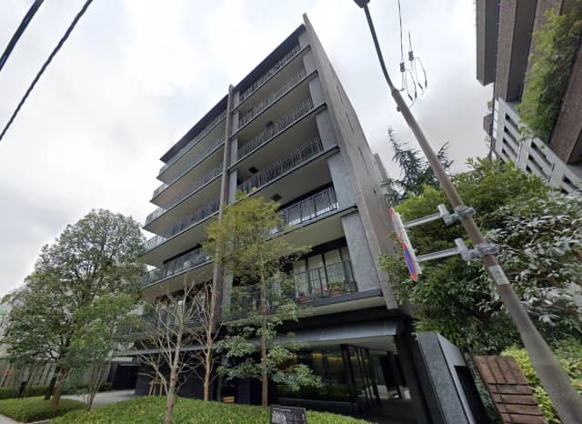 現代的なデザインのマンション外観、バルコニー付き、緑豊かな樹木と低木のあるエントランス