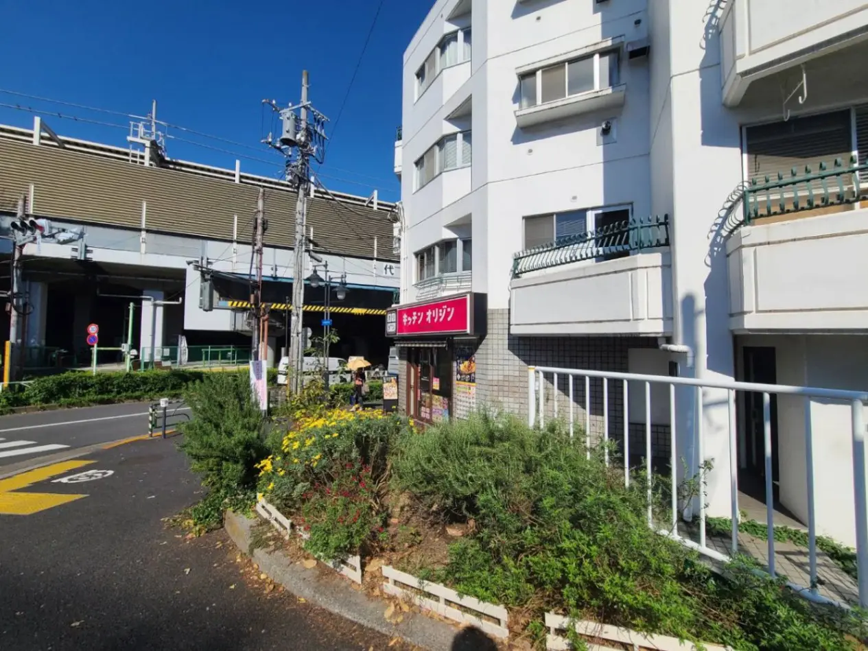 都市の生活感が感じられる街角、アパートと商店、晴天の下での日常風景
