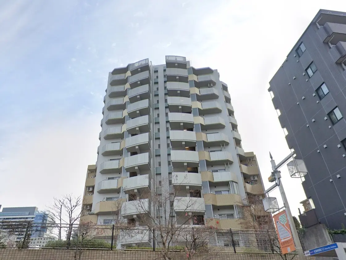 都市地域に位置するモダンなマンションビル、バルコニー付きの外観、青空の下で