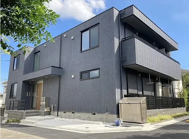 現代的なデザインのグレーの外壁が特徴的な二階建て住宅、明るい日差しと青空