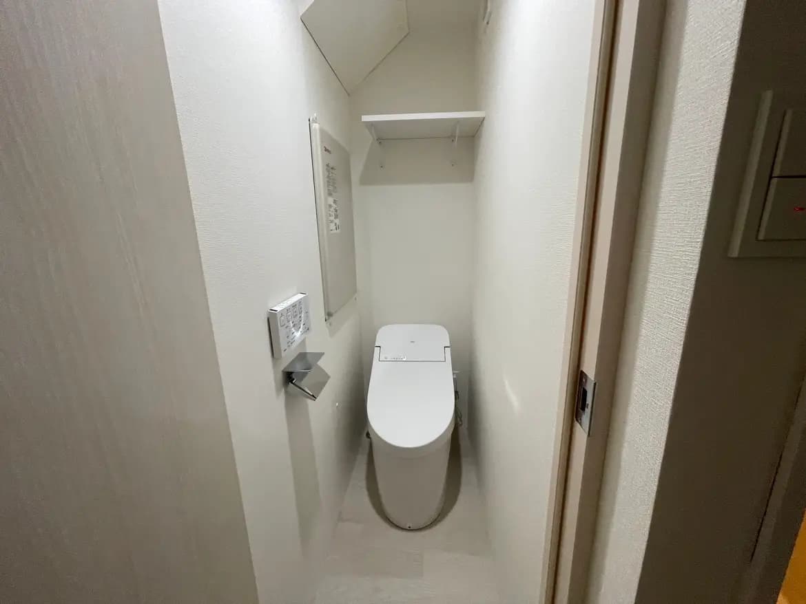 狭い空間に配置されたウォシュレット機能付きトイレ、壁掛けタイプの操作パネル