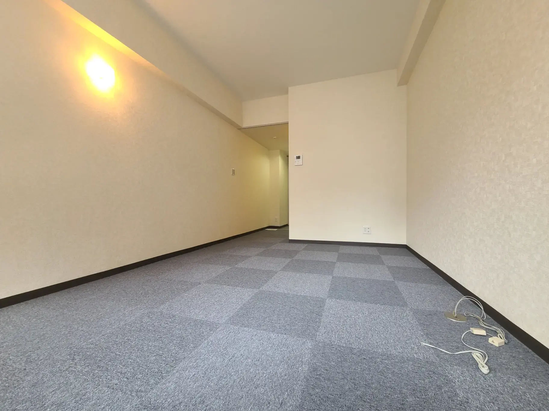 広々とした明るい空間のリビングルーム、シンプルな壁紙とチェッカーパターンのカーペットフロア