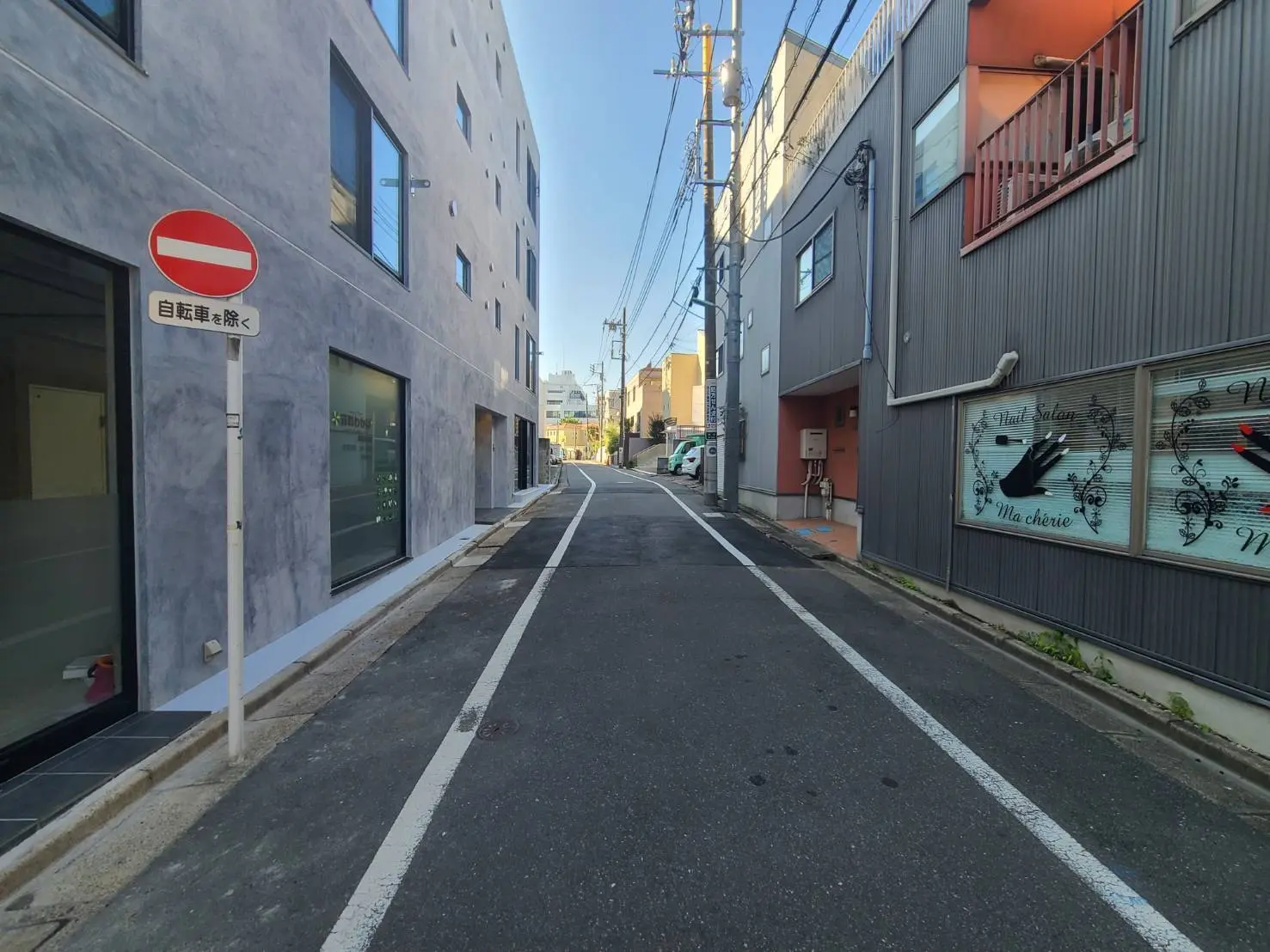 静かな街角の一方通行路、現代的な建物と商業施設、進入禁止標識が見える都市風景