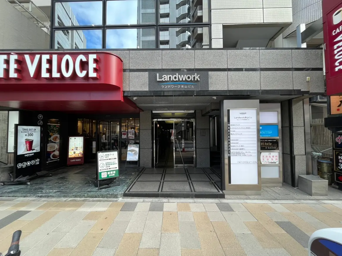 ビルの入り口、上に「Landwork」と記載された看板、左側にカフェヴェローチェの店舗, 案内看板には複数のテナント名が記されている