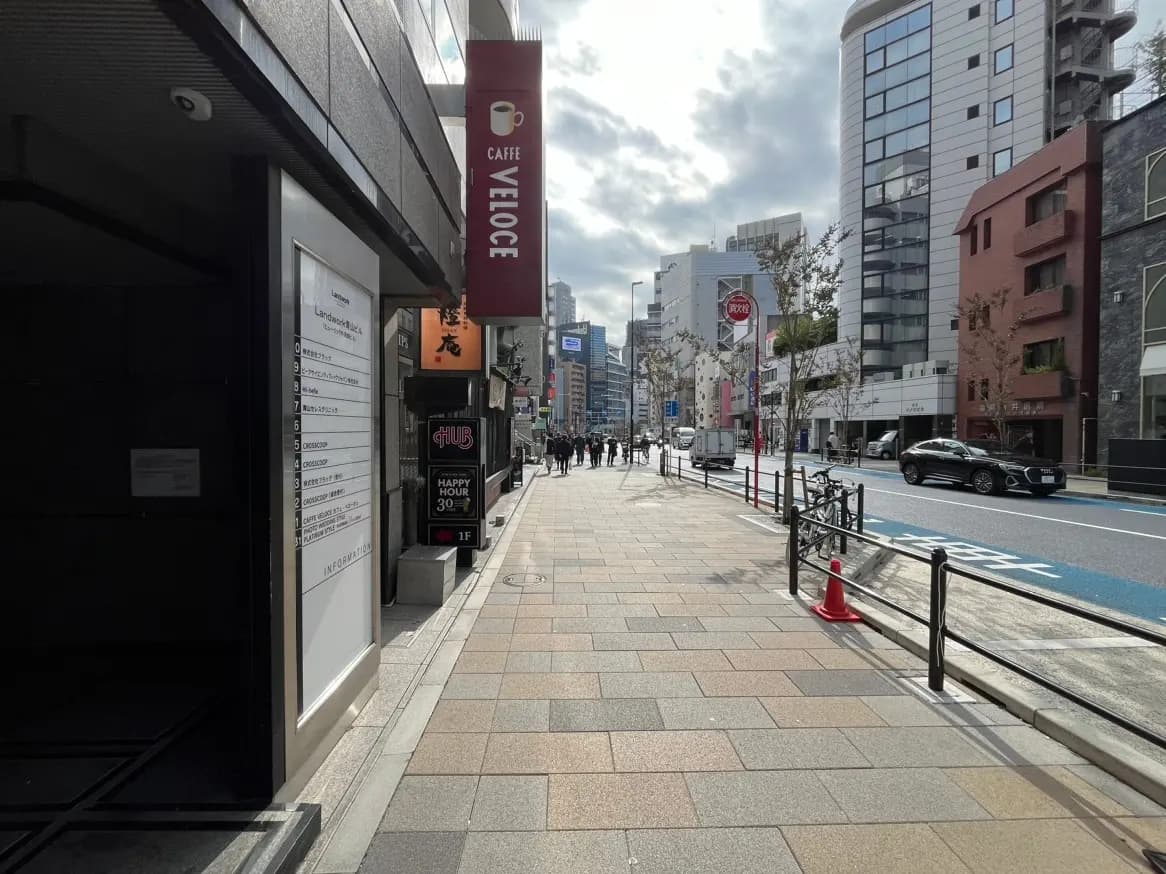 日本の都市の歩道、晴れた日のビルとカフェの外観、道路脇には車が走行