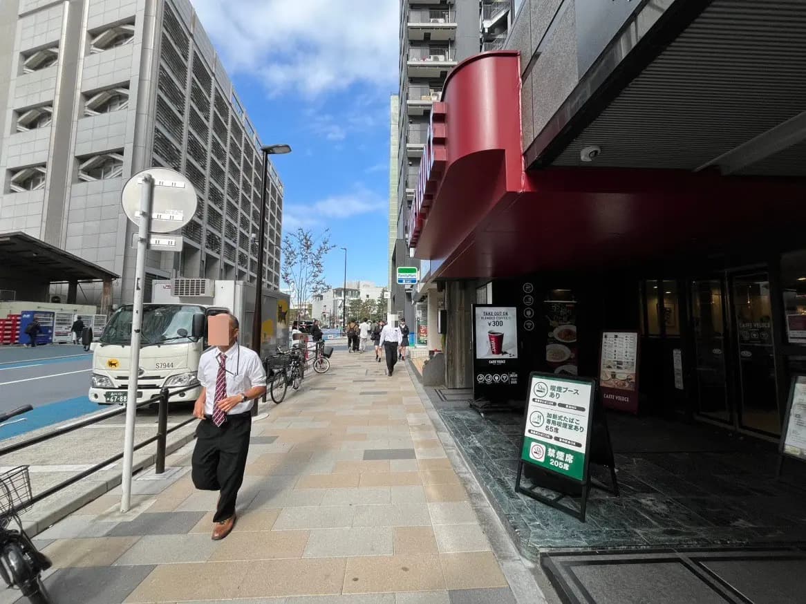 日中に人々が歩いている都市の歩道とビル、日本のカフェの入り口と看板