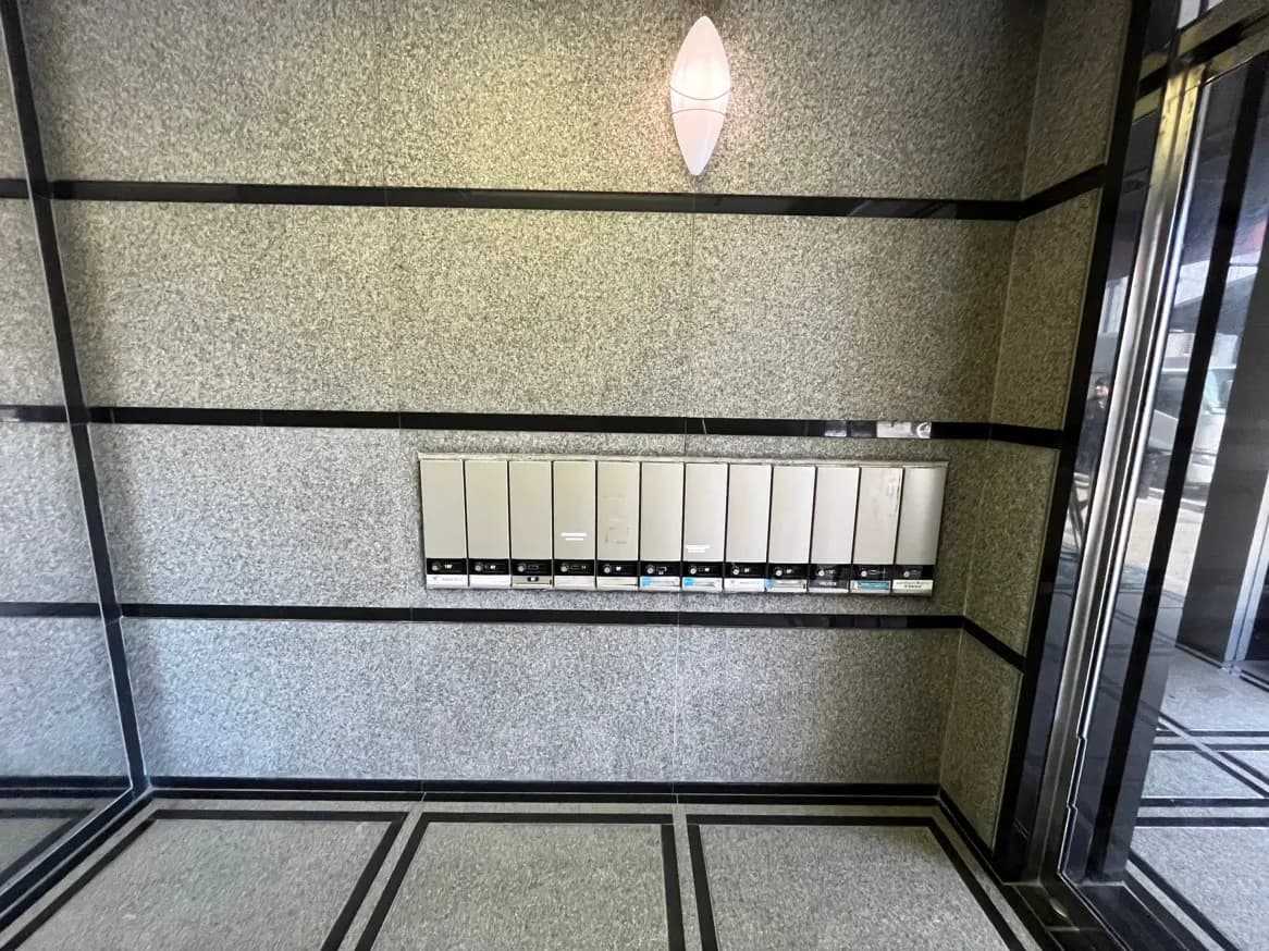 モダンな外観の建物のエントリーに設置された郵便受け、グレーの壁面と黒いラインのデザイン